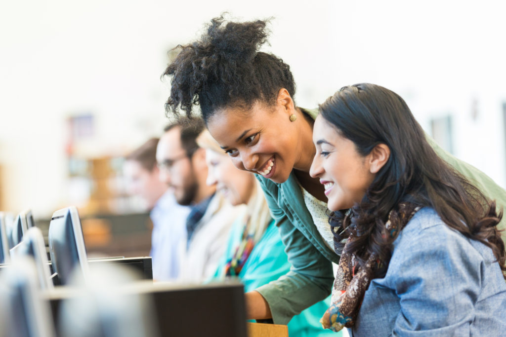 Diverse mid adult students using computers during class in college